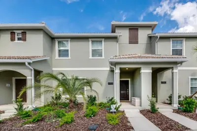 a large white house with palm trees in front of it at 4 Bed Storey Lake Resort With Lazy River townhouse in Kissimmee