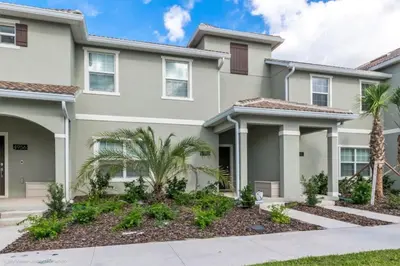 a house with palm trees in front of it at 4 Bed Storey Lake Resort With Lazy River townhouse in Kissimmee