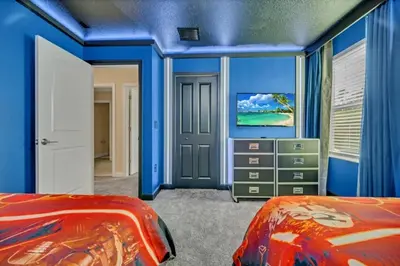 a bedroom with blue walls and a red bed at 9 Bed Storey Lake Villa Pictures Coming Soon home in Kissimmee