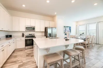 a kitchen with white cabinets and a large island with bar stools at Lovely Cottage Near Disney With Margaritaville Resort & Island H20 Access - 8145Su in Orlando