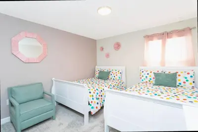 a bedroom with two beds and a chair at Gorgeous 4 Bd w/ Pool at Champions Gate Resort 1020 in Orlando