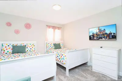 a white bedroom with two beds and a tv at Gorgeous 4 Bd w/ Pool at Champions Gate Resort 1020 in Orlando