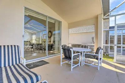 a patio with a table and chairs and a glass door at 8 Mi to Disney World Home with Lanai and Game Room! in Kissimmee