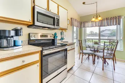 a kitchen with a stove top oven next to a table at 7 Mi to Disney Family-Friendly Home with Pool! in Kissimmee