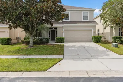 a house with a tree and a driveway at WindsorHills Villa Pool Resort Amenities Minutes to Disney in Orlando