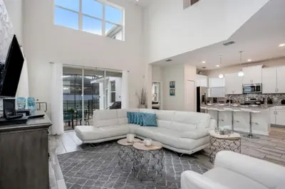 a living room with a white couch and a kitchen at Magical Memories Await at Jimmy Cricket's Retreat in Kissimmee