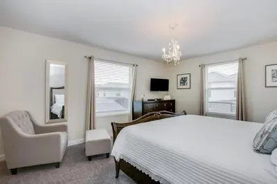 a bedroom with a bed and a chair and windows at Magical Memories Await at Jimmy Cricket's Retreat in Kissimmee