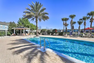 a swimming pool at a resort with palm trees at 6 Mi to WDW Family-Friendly Townhome with Foosball! in Kissimmee