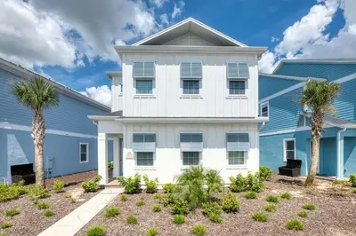 a white house with palm trees in front of it at Comfy Cottage Near Disney With Margaritaville Resort & Island H20 Waterpark Access - 2926Sr in Orlando