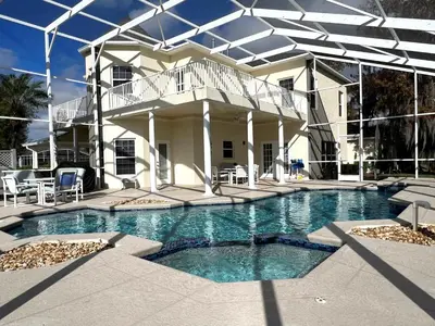 a swimming pool in front of a house at Mickeys Homestead - Stylish 4BR Lakefront Cottage with Huge South Facing Pool Hot Tub BBQ - 2 miles Disney! in Orlando