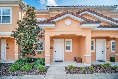 a orange house with a tree in front of it at Regal Oaks Resort Townhouse in Kissimmee
