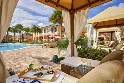 a resort patio with a pool and tables and chairs at Regal Oaks Resort Townhouse in Kissimmee