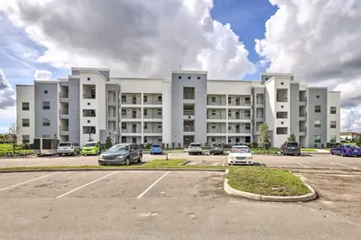 a large white building with cars parked in a parking lot at Kissimmee Condo about 10 Mi to Disney Attractions in Kissimmee