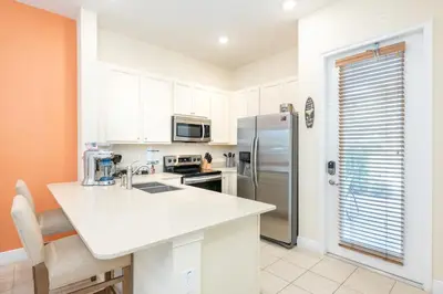 a kitchen with white cabinets and a stainless steel refrigerator at Comfortable Cottage Near Disney With Margaritaville Resort & Island H20 Waterpark Access - 3017Sp in Orlando