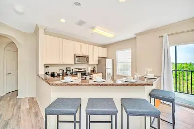 a kitchen with a counter and stools in a room at Spacious 3BR Condo with Pool, near Disney! in Orlando