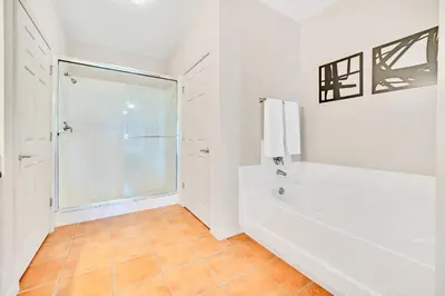 a white bathroom with a tub and a shower at Spacious 2BR Condo with Pool , near Disney! in Orlando