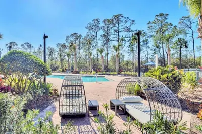 a patio with two chairs and a pool at Spacious 2BR Condo with Pool , near Disney! in Orlando