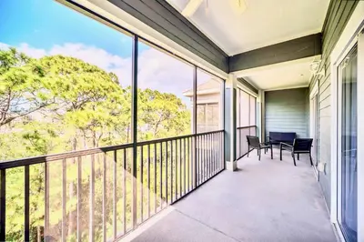 a balcony with a table and chairs and large windows at Spacious 2BR Condo with Pool , near Disney! in Orlando