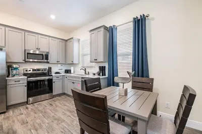a kitchen and dining room with a wooden table and chairs at Dreamy Cottage Near Disney With Margaritaville Resort & Island H20 Waterpark Access - 2944Sr in Orlando