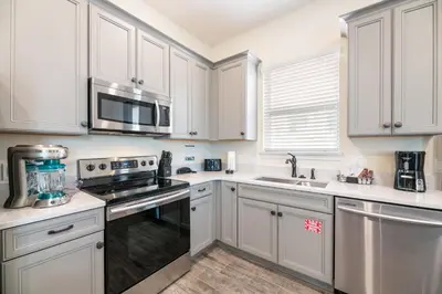 a kitchen with white cabinets and a stove top oven at Dreamy Cottage Near Disney With Margaritaville Resort & Island H20 Waterpark Access - 2944Sr in Orlando