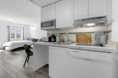 a kitchen with white cabinets and a bed in a room at Cozy Condo on International Dr. Near Universal Studios in Orlando