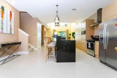 a kitchen with a refrigerator and a table with chairs at Stunning 4Bd Close to Disney @ Magic Village 7614 in Orlando
