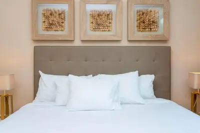 a bedroom with a white bed with three pictures on the wall at Stunning 4Bd Close to Disney @ Magic Village 7614 in Orlando