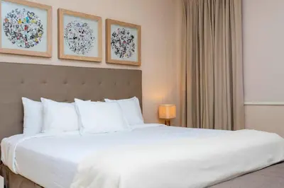 a bedroom with a large white bed and paintings on the wall at Stunning 4Bd Close to Disney @ Magic Village 7614 in Orlando