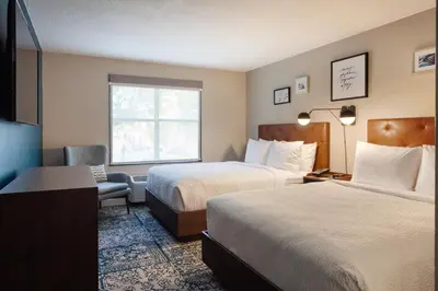 a hotel room with two beds and a chair at Four Points by Sheraton Orlando Convention Center in Orlando