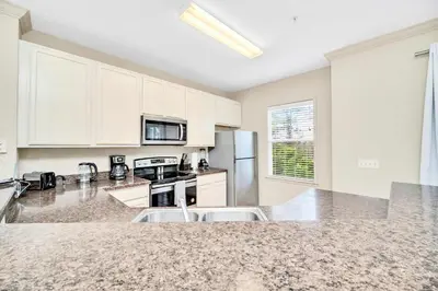 a kitchen with white cabinets and a counter top at Upstay Condo with Outdoor Pool & Sauna in Orlando