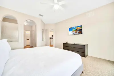 a white bedroom with a white bed and a ceiling fan at Upstay Condo with Outdoor Pool & Sauna in Orlando