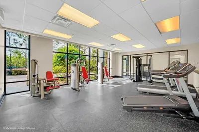 a gym with treadmills and ellipticals and windows at Upstay Condo with Outdoor Pool & Sauna in Orlando