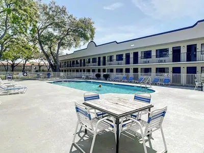 a table and chairs in front of a building with a pool at Stayable Kissimmee West in Kissimmee