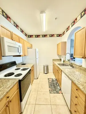 a large kitchen with white appliances and wooden cabinets at Amazing Resort 2 bed condo close to Disney condo in Kissimmee