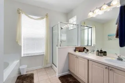 a bathroom with a sink and a shower and a mirror at 4 Bedroom 3 Bath South Facing Pool Spa Villa villa in Kissimmee