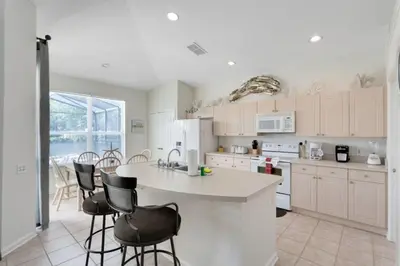 a kitchen with a counter and chairs in it at 4 Bedroom 3 Bath South Facing Pool Spa Villa villa in Kissimmee