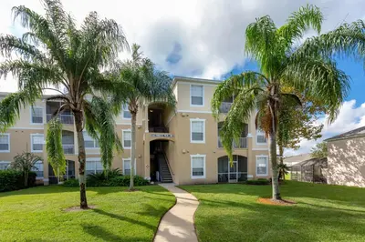 a house with palm trees in front of it at The Great Escape - A spacious 1st floor condo on Windsor Palms Resort - close to Disney in Kissimmee