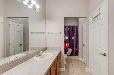 a bathroom with a sink and a toilet and a mirror at The Great Escape - A spacious 1st floor condo on Windsor Palms Resort - close to Disney in Kissimmee