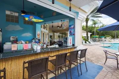 a patio with a bar with chairs and a pool at The Great Escape - A spacious 1st floor condo on Windsor Palms Resort - close to Disney in Kissimmee