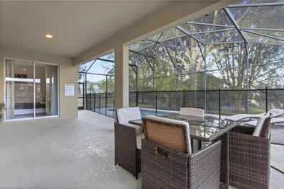a glass house with a patio with chairs and a table at 8503 Themed 7BD Villa- Game room Poolspa in Kissimmee