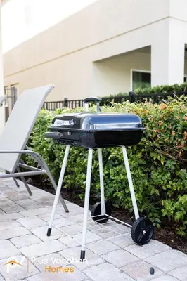 a bbq grill sitting next to a chair at 8503 Themed 7BD Villa- Game room Poolspa in Kissimmee
