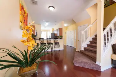 a living room with a staircase and a vase with yellow flowers at 1192SBC South Beach Villa in Kissimmee