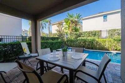 a patio with a table and chairs and a pool at 360LD Encore Magic Villa in Orlando