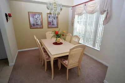 a dining room table with chairs and a vase with flowers at Orlando Vacation Home Near Disney in Kissimmee