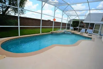 a large swimming pool with an umbrella over it at Orlando Vacation Home Near Disney in Kissimmee