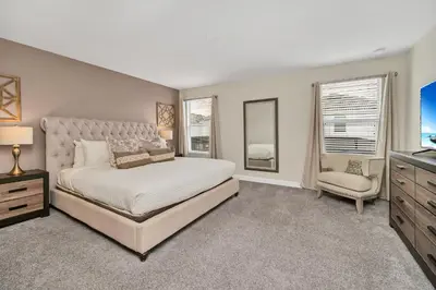 a bedroom with a bed and a tv and a chair at Gorgeous, Modern Home wPrivate Pool in Kissimmee