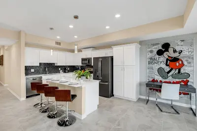 a kitchen with a mickey mouse poster on the wall at NEW Magically Themed Condo w Pool View in Kissimmee