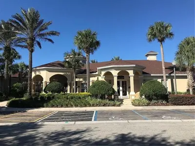 a building with palm trees in a parking lot at 3 BR 2 Miles to Disney, pool, free WiFi and more townhouse in Orlando