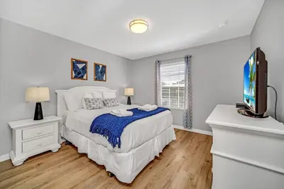 a white bedroom with a bed and a tv at In the heart of Kissimmee Storey Lake Resort 4BD 3BA Pool Townhome 4SL4857 in Kissimmee