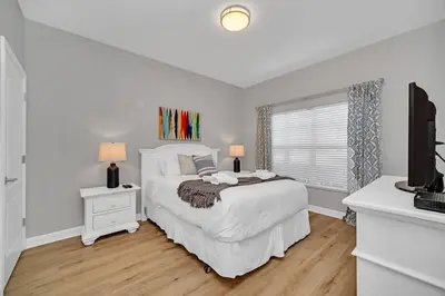 a white bedroom with a bed and a television at In the heart of Kissimmee Storey Lake Resort 4BD 3BA Pool Townhome 4SL4857 in Kissimmee